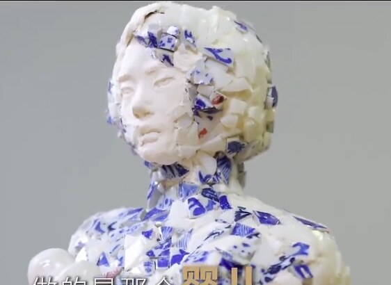 Holding You Together — a mother figure covered in collected porcelain shards holding a smooth white ceramic baby